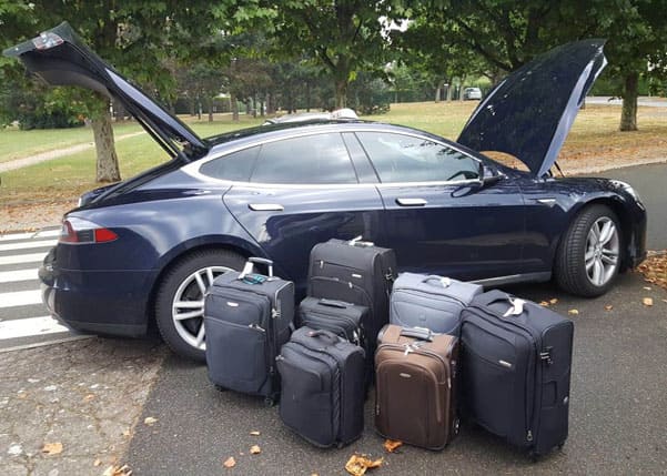 Voiture tesla de couleur bleu foncé avec 7 petites valises devant